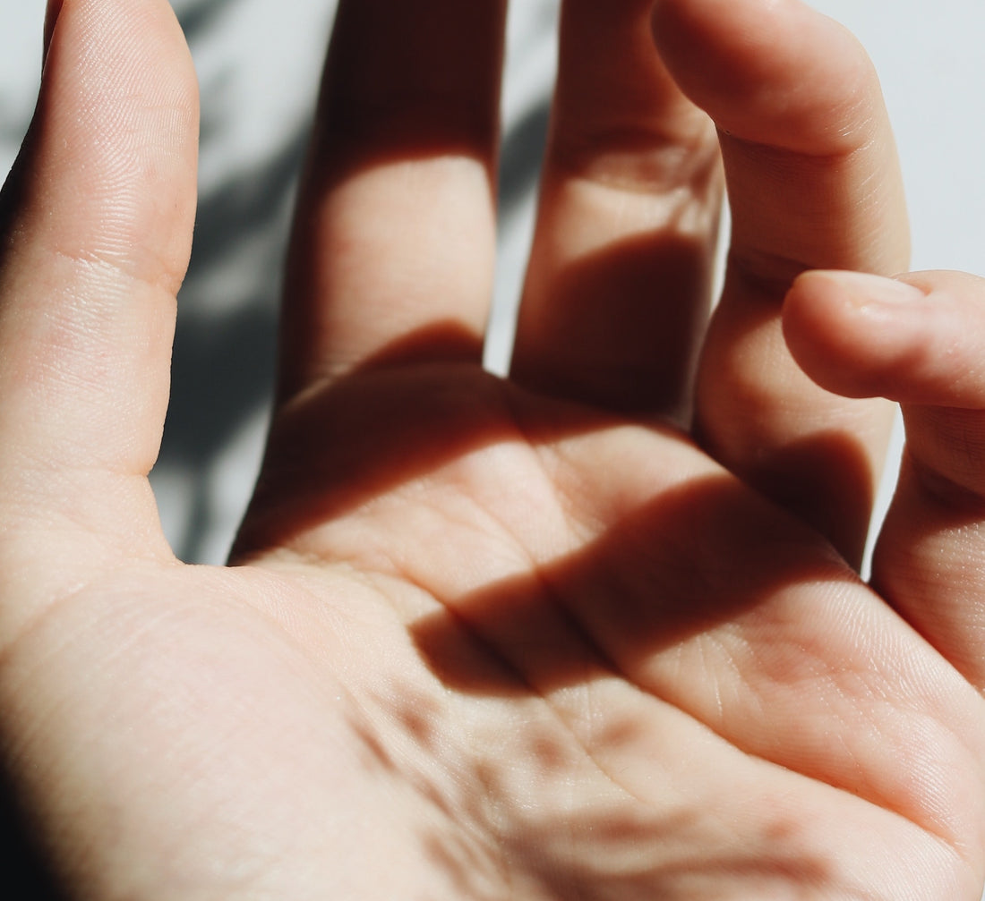 Picture of a palm -up hand with relaxed semi-closed fingers. Light is shining through and casting a shadow.